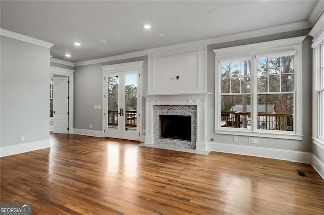 unfurnished living room with crown molding, hardwood / wood-style floors, french doors, and a wealth of natural light