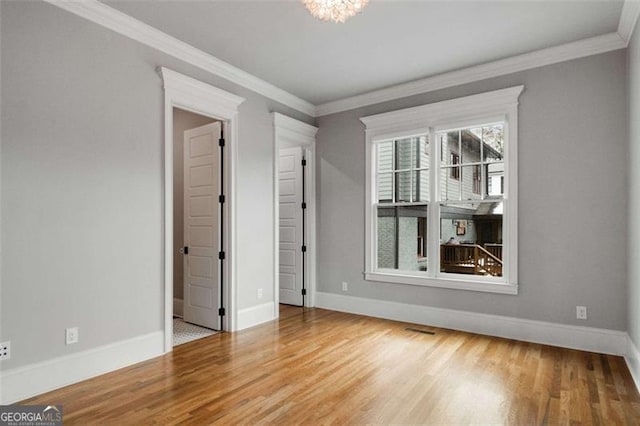 unfurnished room with ornamental molding, hardwood / wood-style floors, and a chandelier