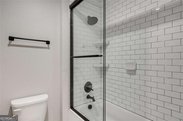 bathroom featuring bath / shower combo with glass door and toilet