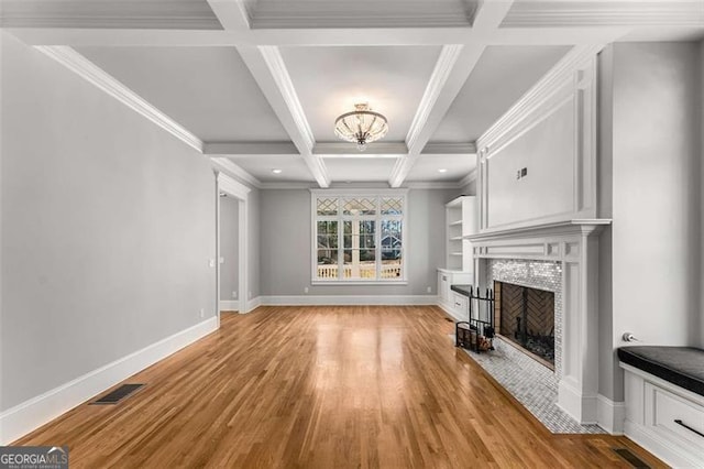 unfurnished living room with crown molding, light hardwood / wood-style flooring, a tile fireplace, beam ceiling, and coffered ceiling