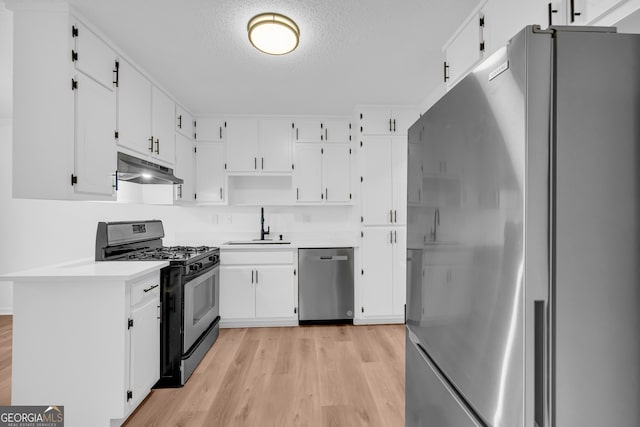 kitchen with appliances with stainless steel finishes, sink, a textured ceiling, and white cabinets