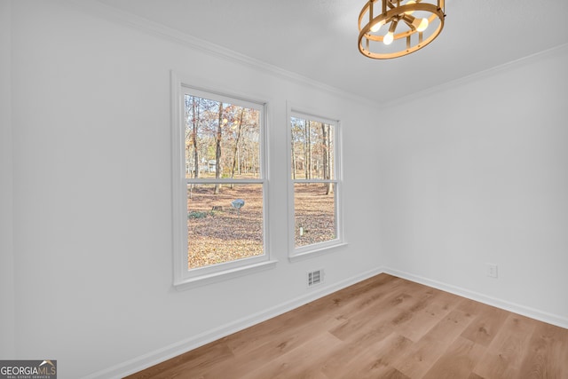 empty room featuring crown molding, an inviting chandelier, and light hardwood / wood-style floors