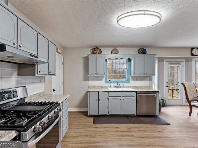 kitchen featuring stainless steel appliances, gray cabinetry, and light wood-type flooring