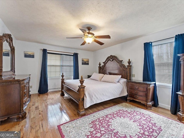 bedroom with ceiling fan, a textured ceiling, and light wood-type flooring