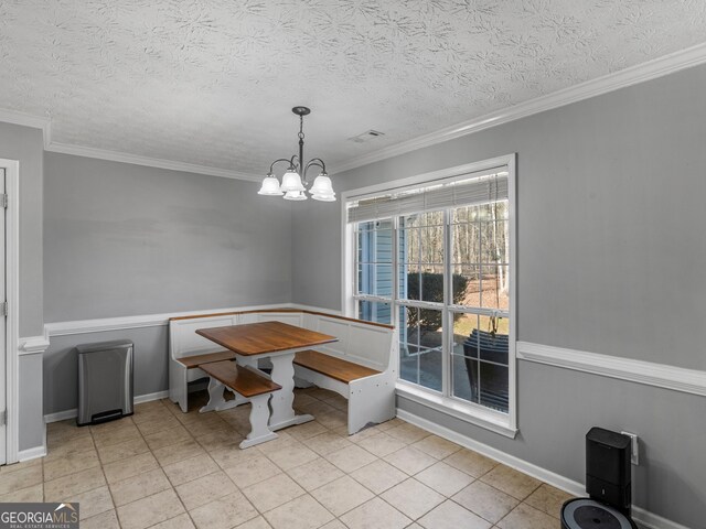 tiled dining area featuring ornamental molding, a textured ceiling, and an inviting chandelier