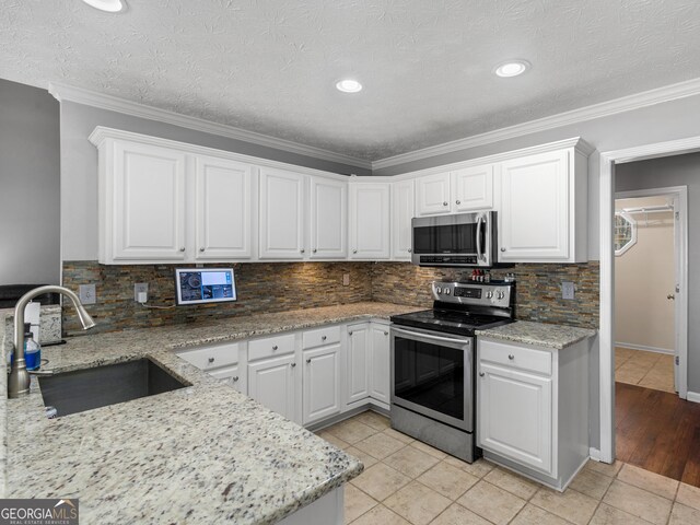 kitchen featuring white cabinetry, appliances with stainless steel finishes, sink, and light tile patterned floors