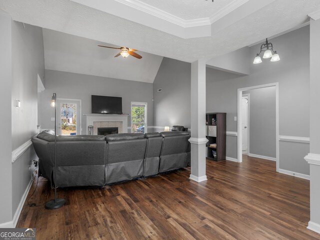 living room with a tiled fireplace, ornamental molding, ceiling fan, dark wood-type flooring, and a textured ceiling