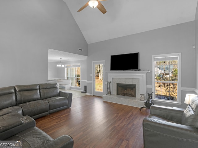 living room featuring high vaulted ceiling, dark wood-type flooring, a wealth of natural light, and a fireplace