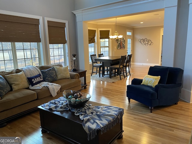 living room with crown molding, light hardwood / wood-style floors, and a notable chandelier