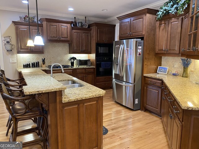 kitchen with tasteful backsplash, sink, pendant lighting, and black appliances