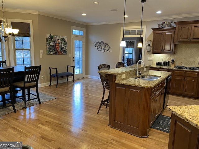 kitchen featuring sink, light hardwood / wood-style flooring, a breakfast bar area, light stone countertops, and a center island with sink