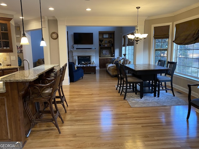 dining space featuring ornamental molding, an inviting chandelier, and light wood-type flooring