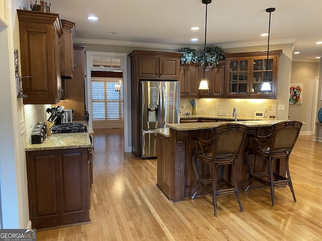 kitchen featuring crown molding, light hardwood / wood-style flooring, hanging light fixtures, stainless steel refrigerator with ice dispenser, and light stone countertops