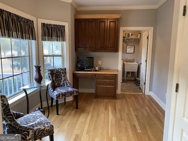 living area featuring ornamental molding, built in desk, and light hardwood / wood-style floors