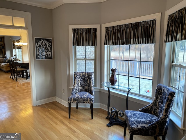 sitting room featuring ornamental molding, hardwood / wood-style floors, and a notable chandelier