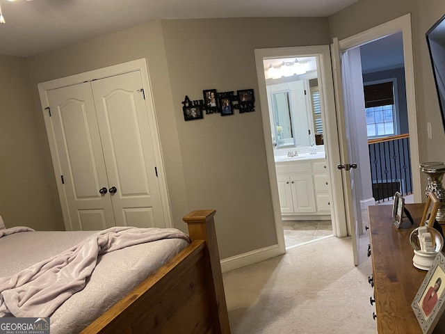 bedroom with sink, light colored carpet, a closet, and ensuite bathroom