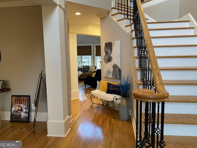 staircase with hardwood / wood-style flooring and ornamental molding