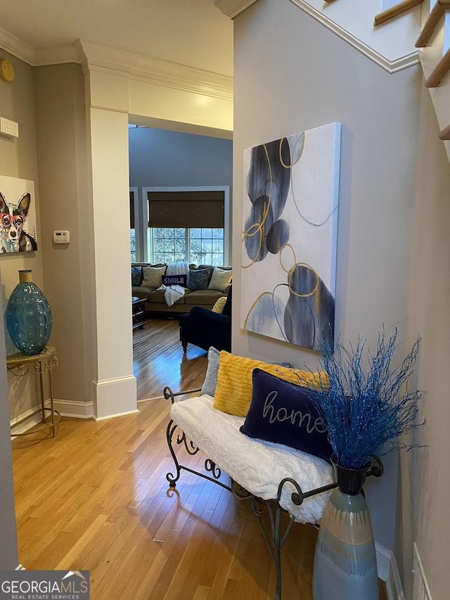 living area featuring crown molding and light hardwood / wood-style flooring