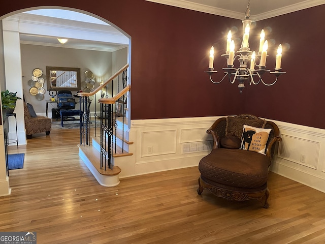 living area featuring wood-type flooring, ornamental molding, and a chandelier