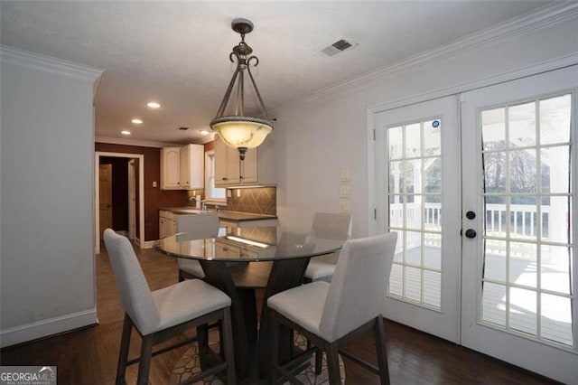 dining room featuring dark wood-type flooring, ornamental molding, and french doors