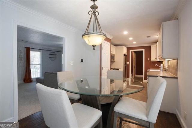 dining room featuring crown molding, dark hardwood / wood-style flooring, and sink