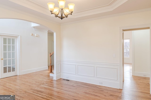 unfurnished room with ornamental molding, an inviting chandelier, and light hardwood / wood-style floors