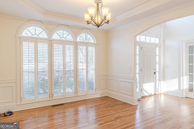 entryway featuring a wealth of natural light, ornamental molding, and light wood-type flooring