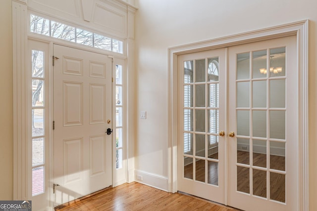 foyer entrance featuring french doors, baseboards, and light wood-style floors