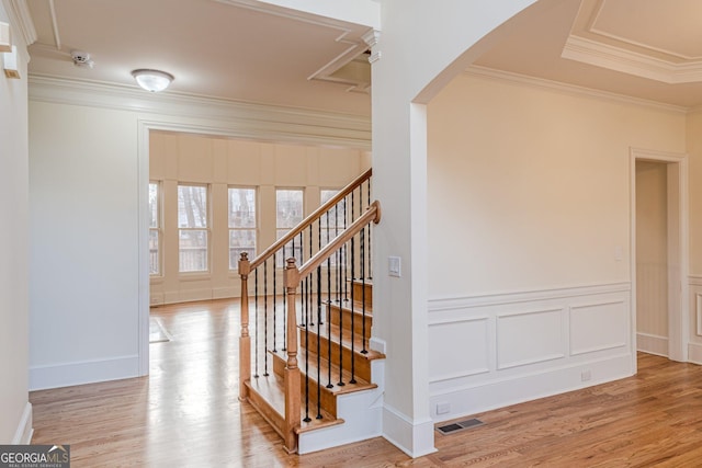 stairway with hardwood / wood-style flooring and ornamental molding