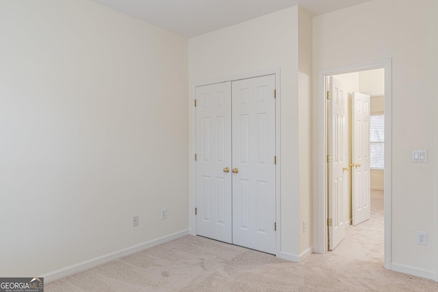 unfurnished bedroom with light colored carpet and a closet