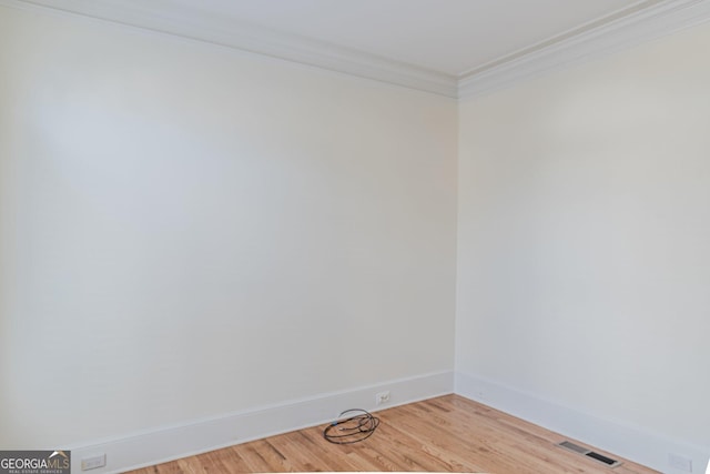 empty room with crown molding and light hardwood / wood-style floors