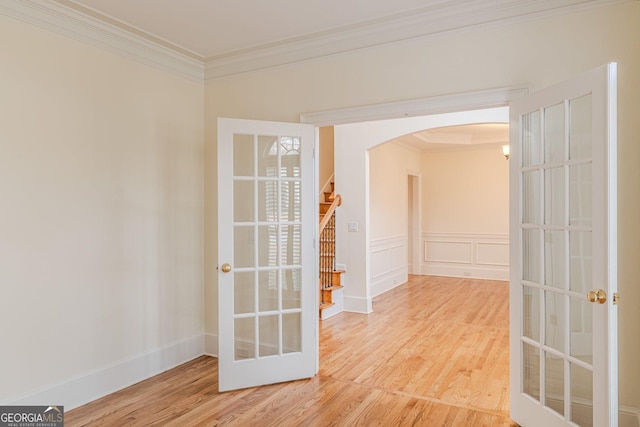 empty room featuring light hardwood / wood-style floors, ornamental molding, and french doors