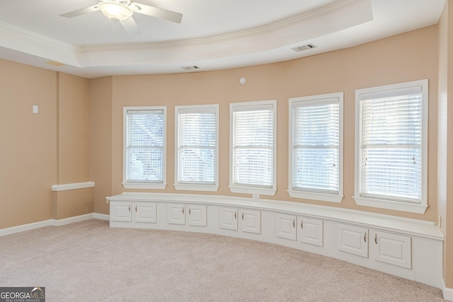 carpeted empty room featuring crown molding, ceiling fan, and a raised ceiling