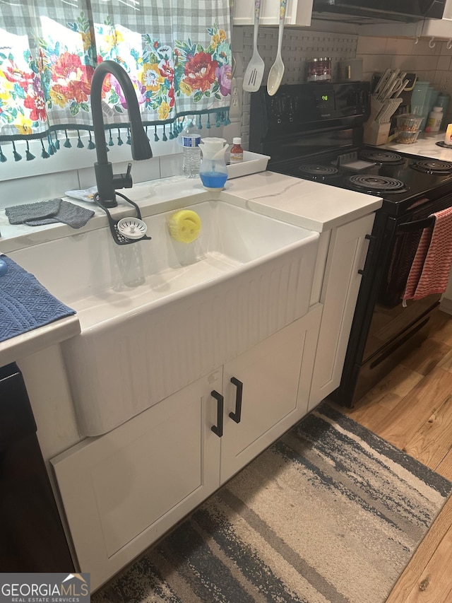 kitchen featuring white cabinets, dark wood-style floors, black range with electric stovetop, light countertops, and backsplash