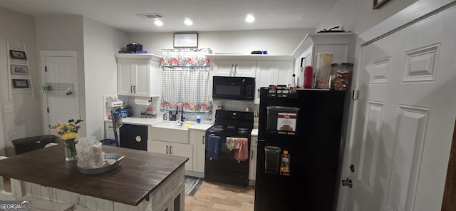 kitchen with black appliances, white cabinetry, light countertops, and a sink