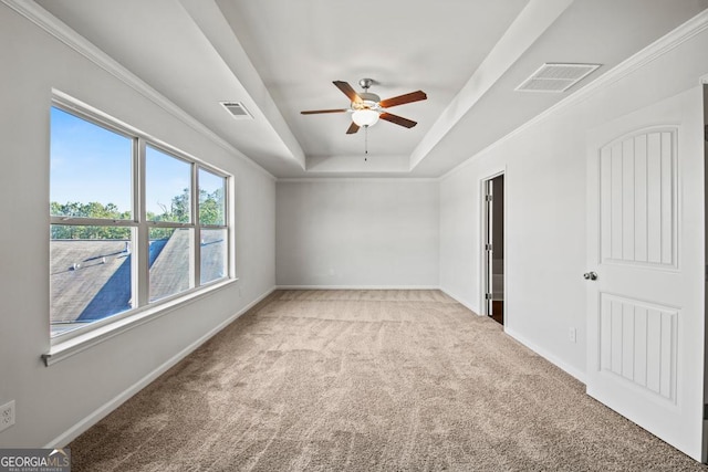 carpeted empty room with a raised ceiling, ornamental molding, and ceiling fan