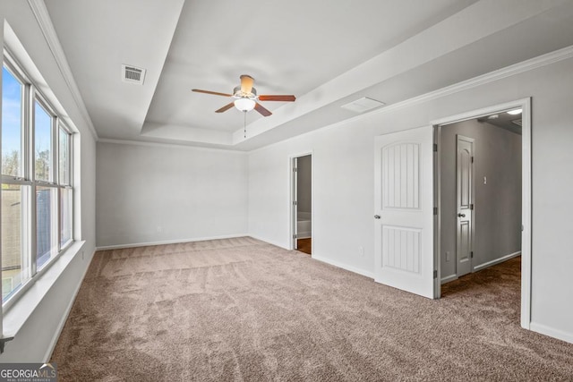 spare room with crown molding, ceiling fan, a tray ceiling, and dark colored carpet