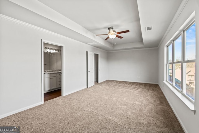 unfurnished bedroom featuring crown molding, carpet, ensuite bath, and a tray ceiling