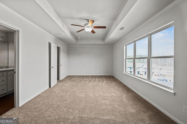 unfurnished bedroom with crown molding, ceiling fan, a raised ceiling, and carpet floors