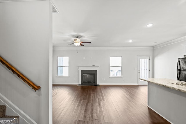 unfurnished living room with dark hardwood / wood-style flooring, a wealth of natural light, ornamental molding, and ceiling fan