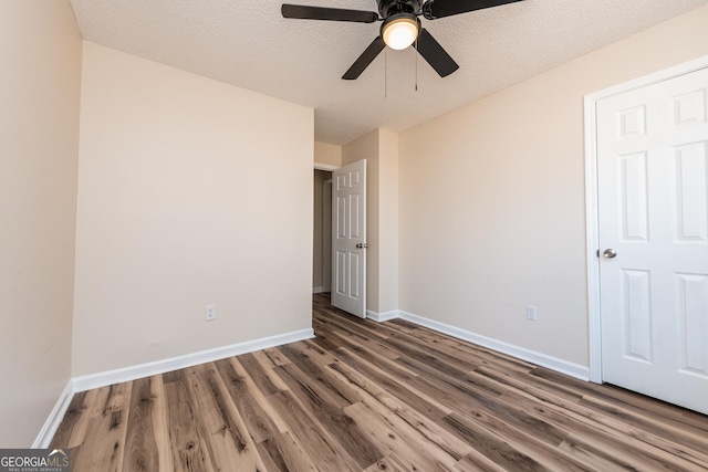 unfurnished bedroom featuring dark hardwood / wood-style floors, a textured ceiling, and ceiling fan