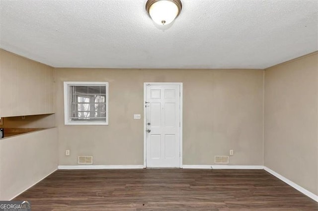 interior space with a textured ceiling and dark hardwood / wood-style flooring