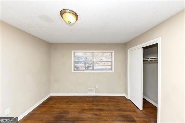 unfurnished bedroom featuring dark hardwood / wood-style flooring and a closet