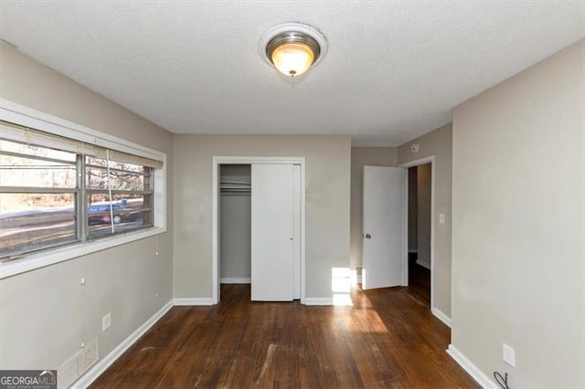 unfurnished bedroom with dark hardwood / wood-style flooring, a closet, and a textured ceiling