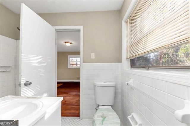 bathroom featuring vanity, toilet, and tile walls