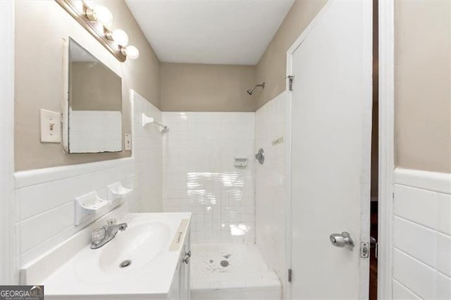 bathroom with vanity, tile walls, and tiled shower