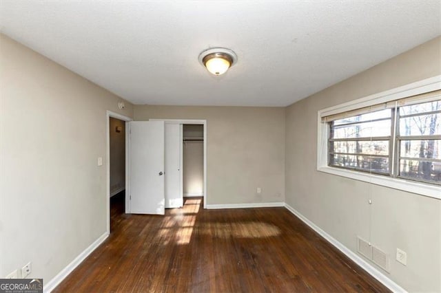 unfurnished bedroom with dark wood-type flooring and a closet