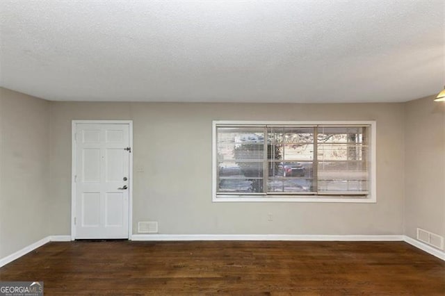 unfurnished room with dark hardwood / wood-style floors and a textured ceiling