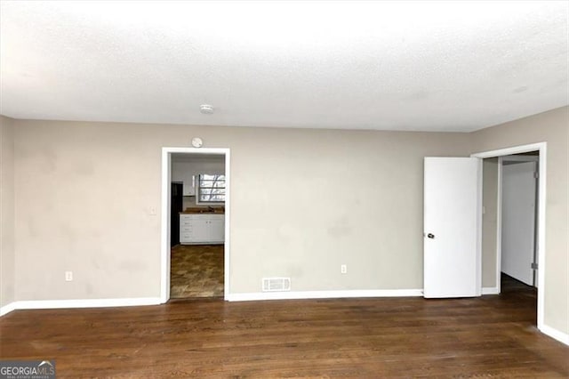 empty room featuring dark wood-type flooring and a textured ceiling