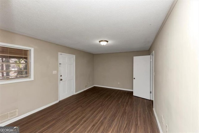 empty room with dark wood-type flooring and a textured ceiling